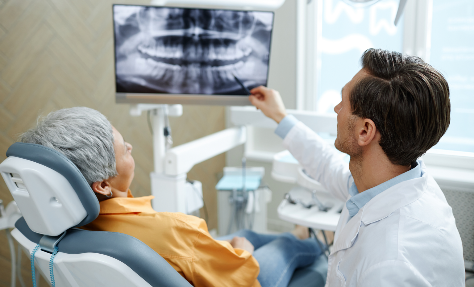 Oral and maxillofacial surgeon reviewing a patient's dental X-ray during a surgical consultation