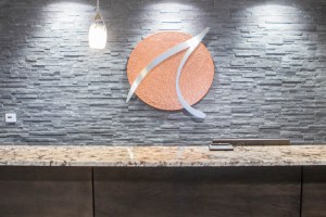 Reception counter with granite top, gray stone wall, and circular orange logo with silver swoosh